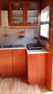 a kitchen with wooden cabinets and a sink and counters at dom letni in Stare Jabłonki