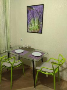 a glass table with two chairs and a painting on the wall at Хорошая однокомнатная квартира в центре города in Shostka