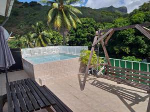 - une piscine avec un banc et un palmier dans l'établissement Apartment Studio Halfon, à Moorea