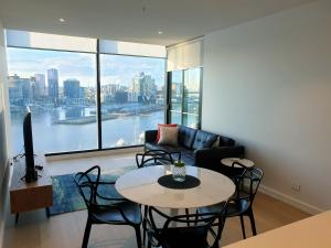 a living room with a table and chairs and a couch at Orange Stay at Collins Wharf in Melbourne