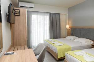 a hotel room with two beds and a television at Regina Mare Hotel in Paralia Katerinis