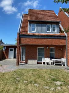 ein Haus mit einer Terrasse, einem Tisch und Stühlen in der Unterkunft Haus Windjammer in Friedrichskoog