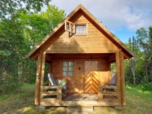 eine Hütte mit einer Terrasse, einem Tisch und Stühlen in der Unterkunft Intsu cabin ''Marju Kuut'' in Liiva