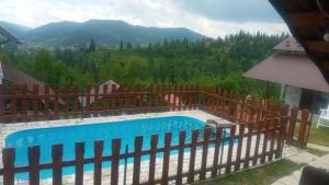 a pool with a fence and mountains in the background at Біля лісу Шале з двома спальнями in Slavske