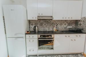 a white kitchen with white cabinets and a refrigerator at Burtnieka ezera māja in Valmiera