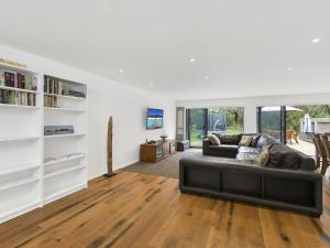 a living room with a black couch and wooden floors at Paringa 15 Anglesea Beach House in Anglesea