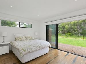a white bedroom with a bed and a large window at Paringa 15 Anglesea Beach House in Anglesea