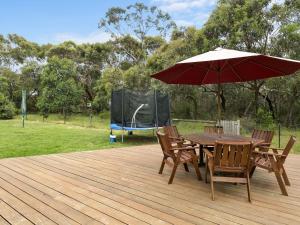 a wooden deck with a table and chairs with an umbrella at Paringa 15 Anglesea Beach House in Anglesea