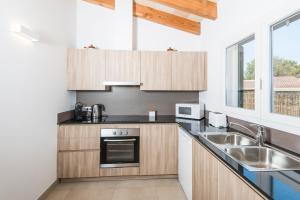 a kitchen with wooden cabinets and a sink at Villa Calan Bosch Es Bruc in Cala'n Bosch