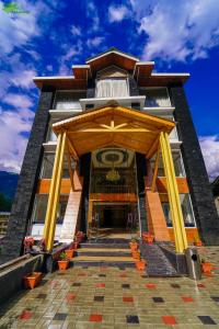 een gebouw met een houten structuur met gele zuilen bij Abhilashi Residency & Spa - Centrally Heated & Air Cooled in Manāli