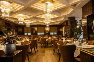 a dining room with tables and chairs and chandeliers at Hotel Golden Palace in Shkodër