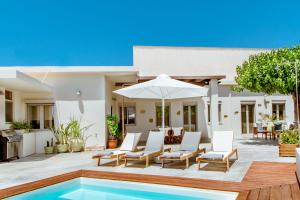 a villa with a swimming pool with chairs and an umbrella at Chania Paradise Retreat - Falasarna Villa Nostalgia in Plátanos