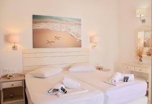 a white bedroom with a bed with towels on it at Aegeo Inn in Antiparos