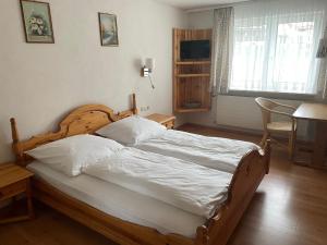 Schlafzimmer mit einem Holzbett mit weißer Bettwäsche in der Unterkunft Wertacher Hof in Oy-Mittelberg