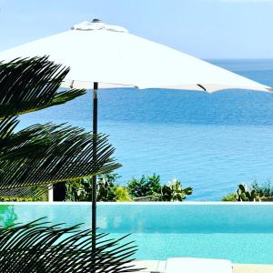 una sombrilla blanca sentada junto a una piscina en B&Bilfortesulmare, en Ventimiglia