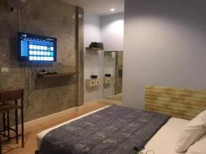 een slaapkamer met een bed en een tv aan de muur bij NONKAJA HOSTEL in Pak Chong