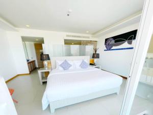 una camera da letto con un grande letto bianco in una stanza di Beach Walk Boutique Resort a Bangsaen