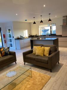 a living room with a couch and a kitchen at The Grasslands Holiday Home, in Cork