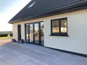 a white building with black windows and a roof at The Grasslands Holiday Home, in Cork