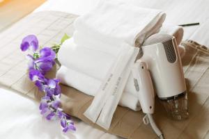 a hair dryer and towels and purple flowers on a table at NAKAZ Machiya , Osaka Umeda in Osaka
