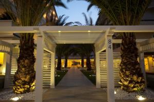 a walkway with palm trees in front of a building at Villa Del Mare Spa Resort in Cervia