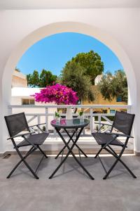 stół i krzesła na balkonie z różowymi kwiatami w obiekcie Kasteli Luxury Rooms w mieście Perissa