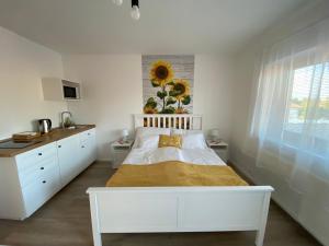 a white bedroom with a bed and a sunflower on the wall at FarmerLand in Abádszalók