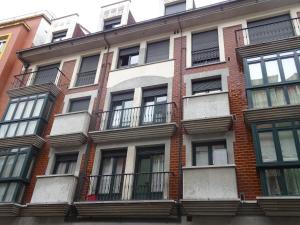 Edificio alto de ladrillo con ventanas y balcones en Apartamento de La Casona de Riomera, en Oviedo