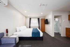 um quarto de hotel com uma cama e um sofá em 311 Motel Riccarton em Christchurch