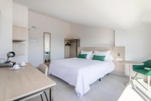 a white bedroom with a large bed and a table at Halley Hotel & Apartments Affiliated by Meliá in Benidorm