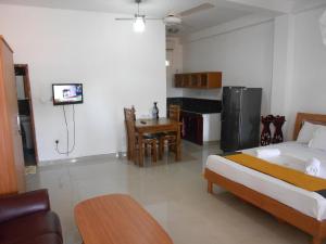 a room with a bed and a table and a kitchen at Shanith Guesthouse Negombo in Negombo