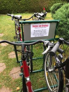 deux vélos garés à côté d'un panneau dans l'herbe dans l'établissement Pension zum Brauhaus, à Stralsund