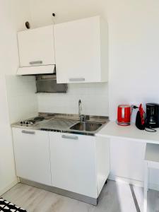 cocina blanca con fregadero y fogones en Bottrigo Apartment, en Bardolino