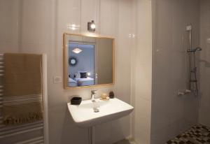 Baño blanco con lavabo y espejo en HOTEL COTE PHARE, en Contis-les-Bains