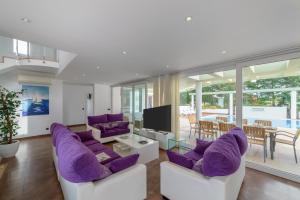 a living room with purple chairs and a tv at Villa Santandria Grupo Seranova Luxury Hotel in Ciutadella