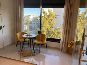 a table and chairs in a room with a large window at RyLux Suits in Ramallah