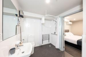 a white bathroom with a sink and a bed at 311 Motel Riccarton in Christchurch +70 photos