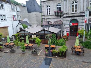 un restaurante al aire libre con mesas, sillas y sombrillas en Alarea, en La-Roche-en-Ardenne