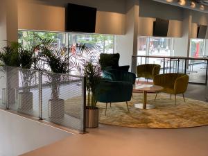 a waiting room with chairs and a table and a rug at IBIS Styles Kaunas Centre in Kaunas