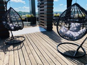 two swinging chairs on a deck with a view at IBIS Styles Kaunas Centre in Kaunas