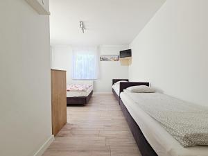 two beds in a room with white walls and wooden floors at Chatka Morska in Karwia