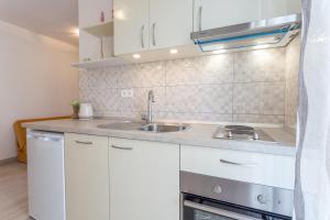 a kitchen with white cabinets and a sink at Apartments Sanja in Hvar