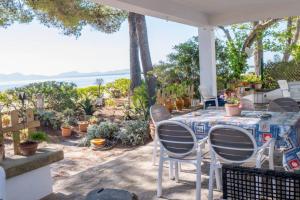 a table and chairs on a patio with a view of the ocean at Waterfront 3 Bedroom Beach Apartment in Alcudia