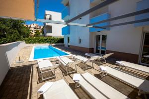 a patio with white chairs and a swimming pool at Villa Stipe in Podstrana