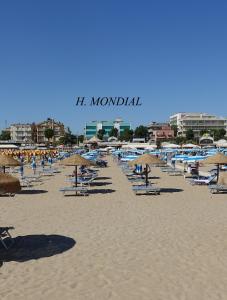 a beach with chairs and umbrellas and people on it at Hotel Mondial in Rimini