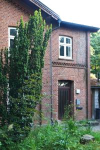 a red brick house with a large tree in front of it at Ferienhof Möltgen in Bosau