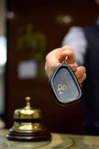 a hand holding a key to a gold bell at Hotel Di Stefano in Pisa