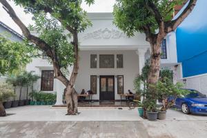 a white house with trees in front of it at Family Homestay Syariah Cirebon Mitra RedDoorz in Cirebon