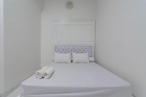 a white bedroom with a white bed with two towels at Family Homestay Syariah Cirebon Mitra RedDoorz in Cirebon