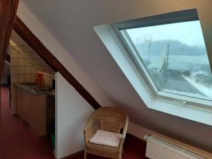 een zolderkamer met een raam en een stoel bij SLEEP & GO! Self service rooms with community kitchen in Nittel